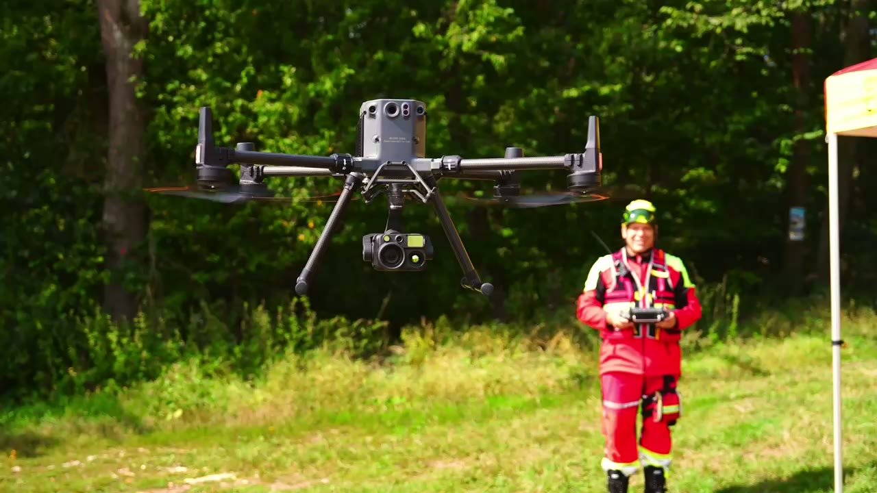 Drone hovering in front of an operator in an open field